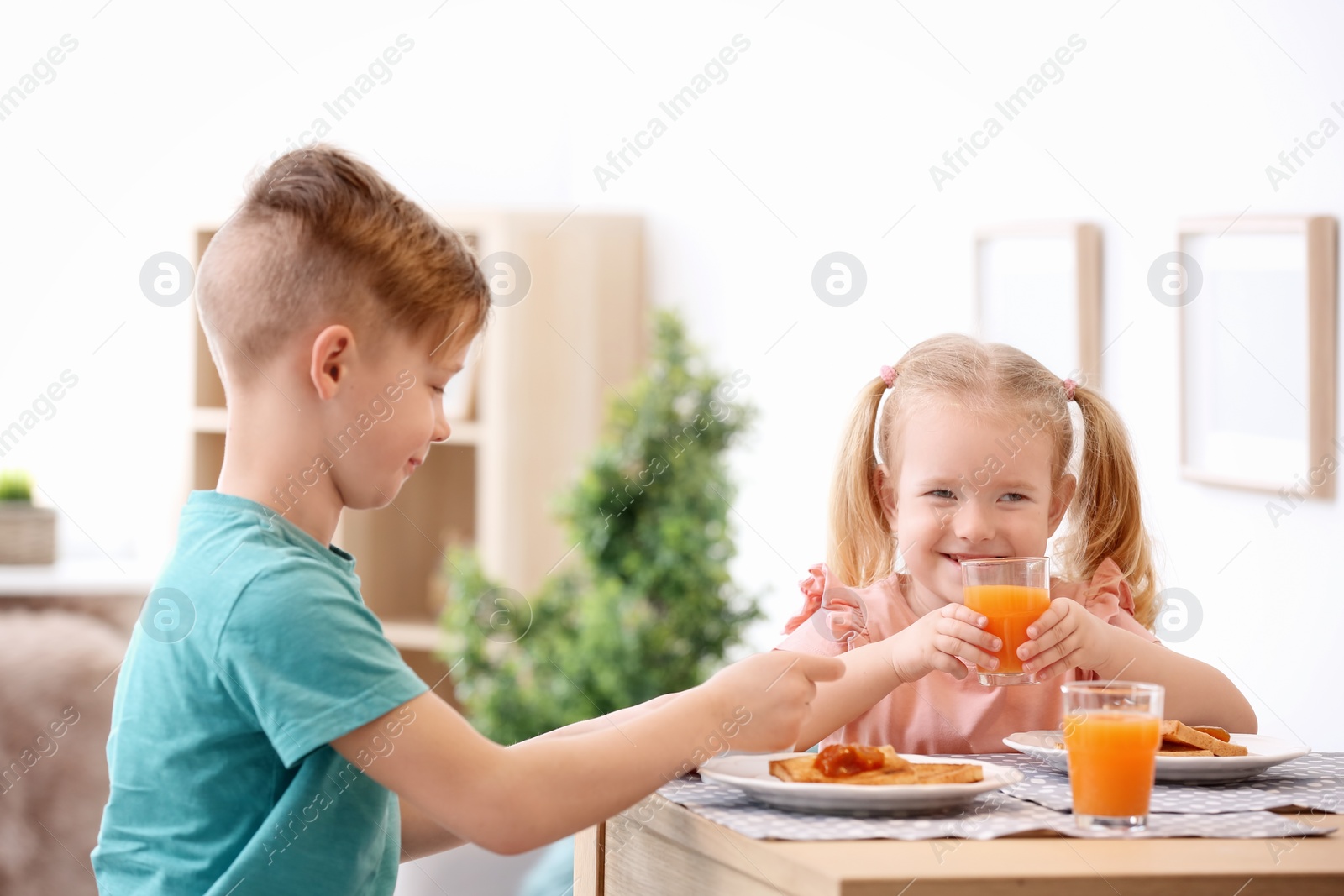 Photo of Adorable little children eating tasty toasted bread with jam at table