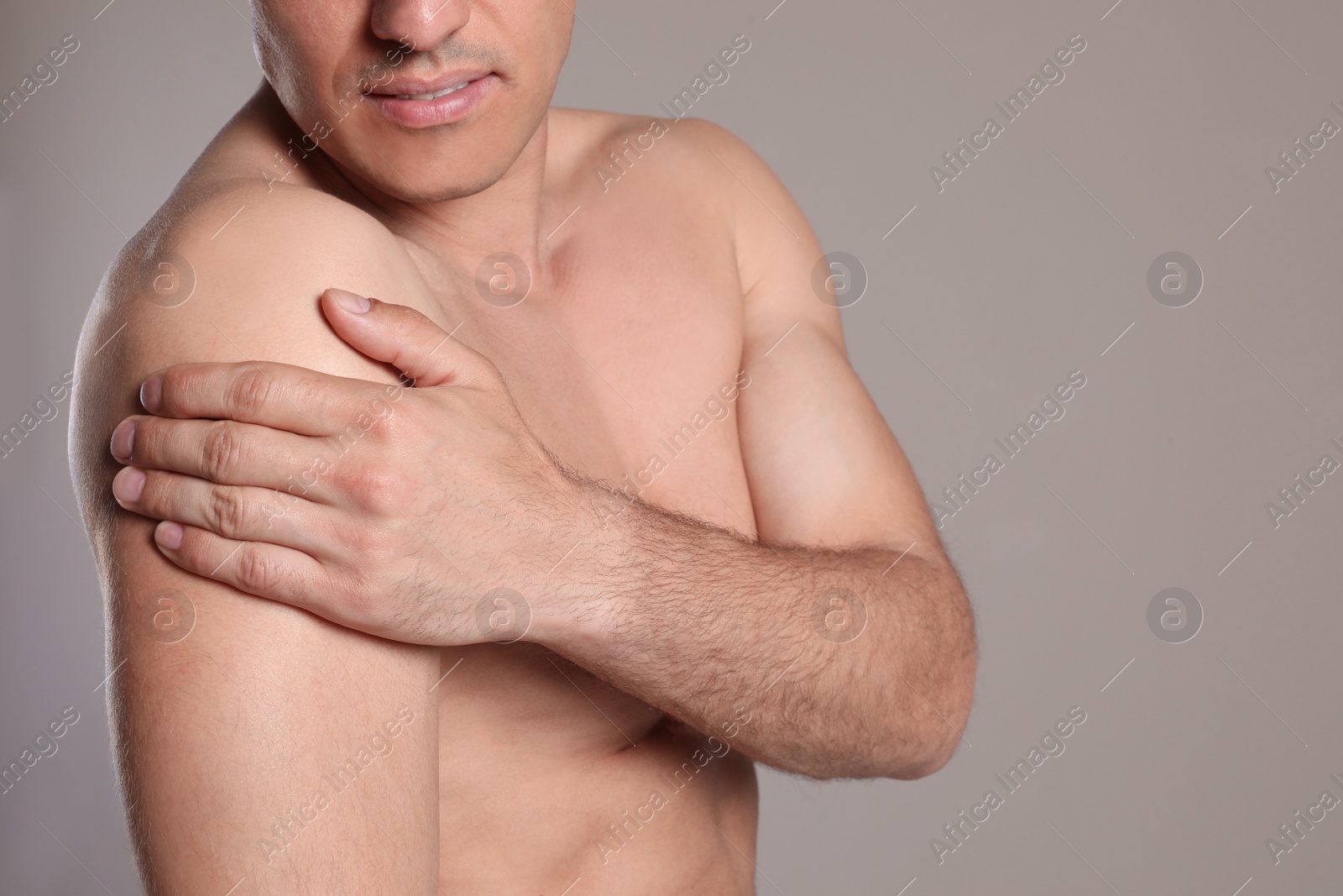 Photo of Man suffering from shoulder pain on beige background, closeup