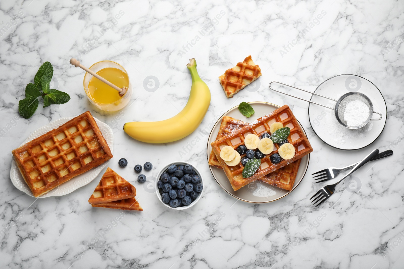 Photo of Delicious Belgian waffles and ingredients on white marble table, flat lay