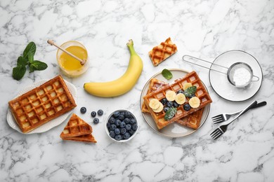 Photo of Delicious Belgian waffles and ingredients on white marble table, flat lay