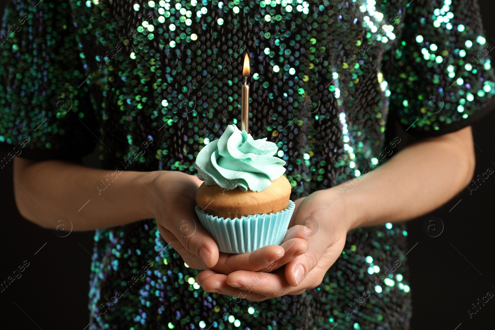 Photo of Woman holding delicious birthday cupcake with burning candle, closeup