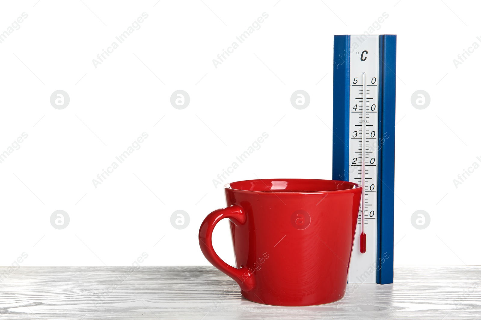Photo of Thermometer and cup of hot tea on wooden table against white background. Space for text