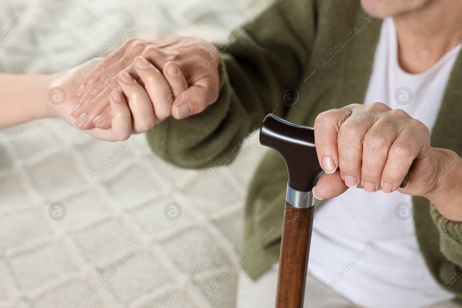 Photo of Caregiver and elderly woman with walking cane at home, closeup