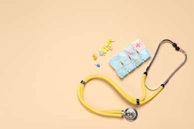 Stethoscope and pills on beige background, flat lay. Space for text