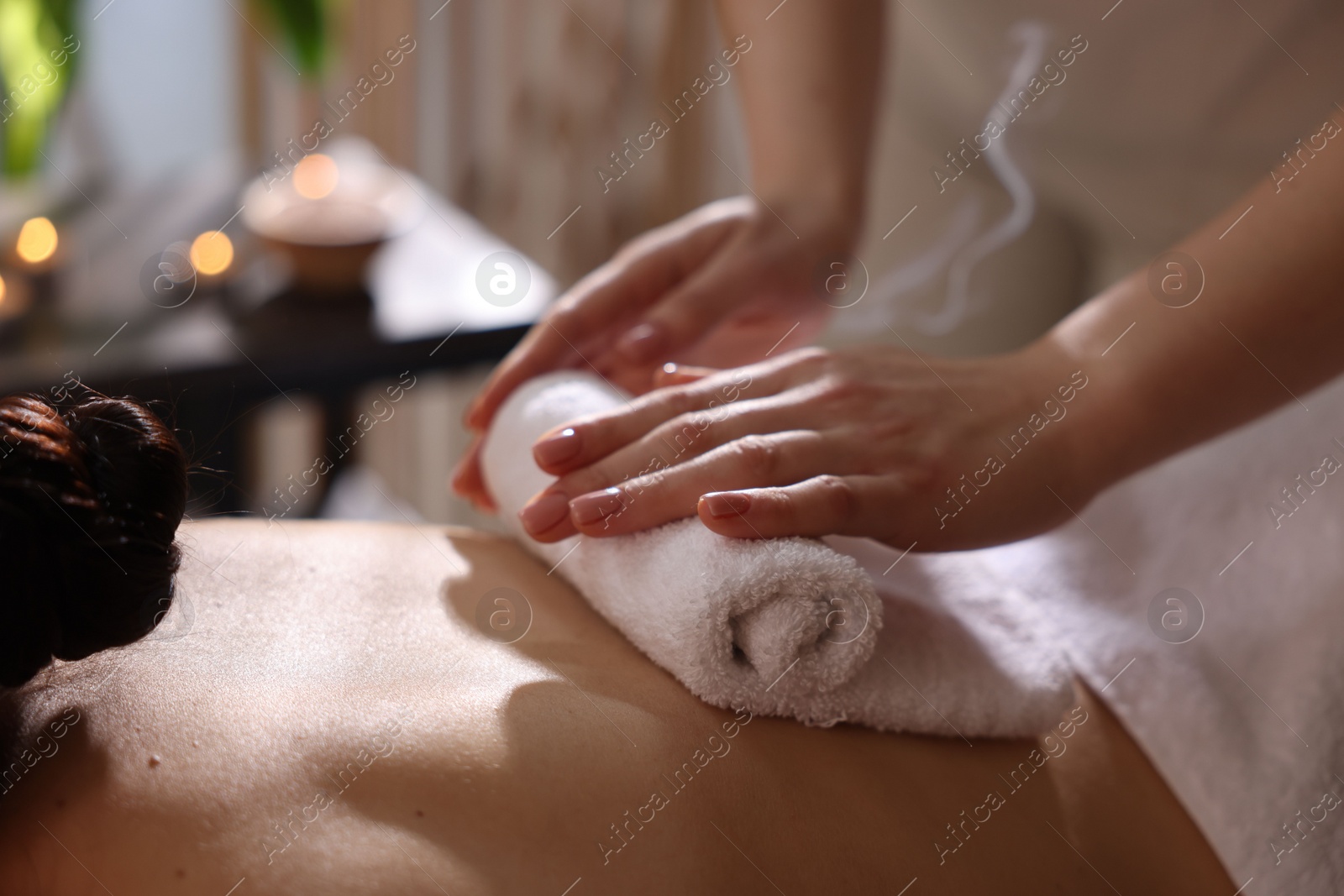 Photo of Spa therapy. Beautiful young woman lying on table during hot towel massage in salon, closeup