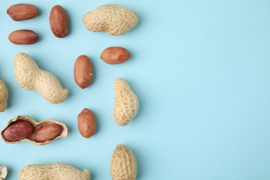 Photo of Fresh peanuts on light blue table, flat lay. Space for text