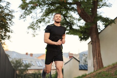 Photo of Attractive sporty man in fitness clothes jogging outdoors