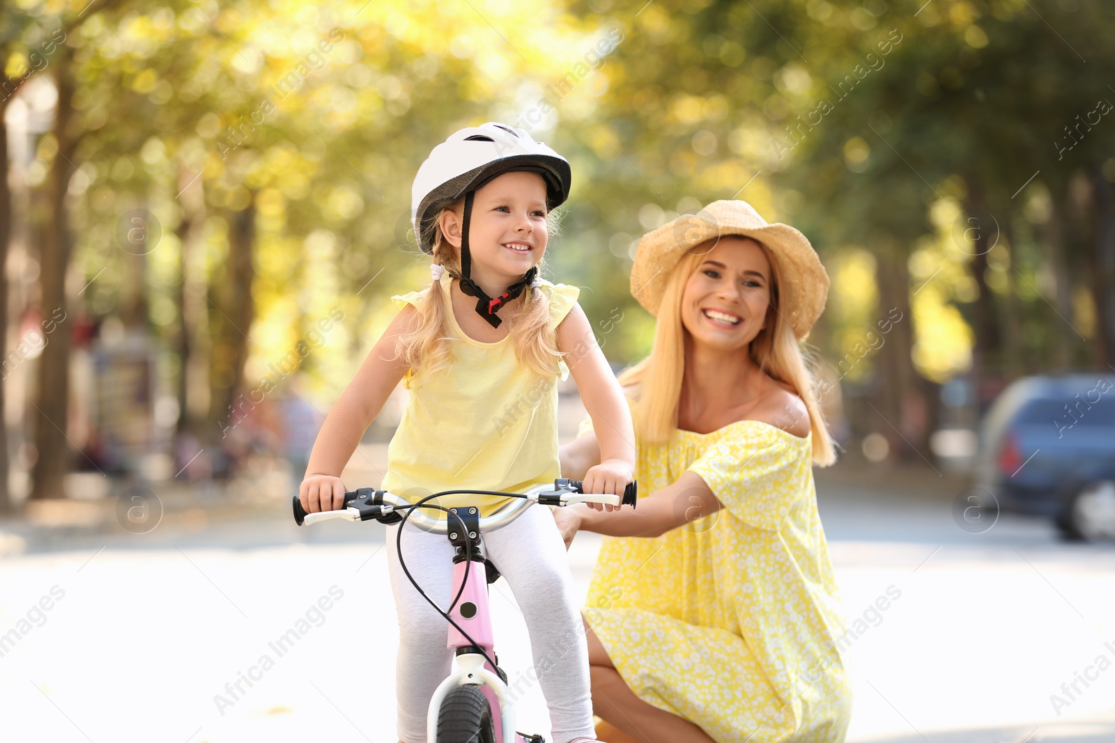Photo of Mother teaching daughter to ride bicycle on street