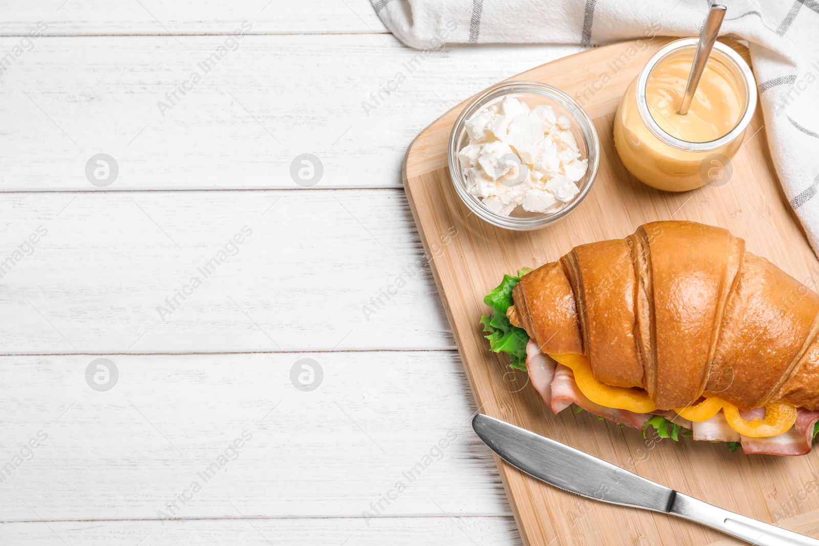 Photo of Tasty croissant sandwich with ham on white wooden table, flat lay. Space for text