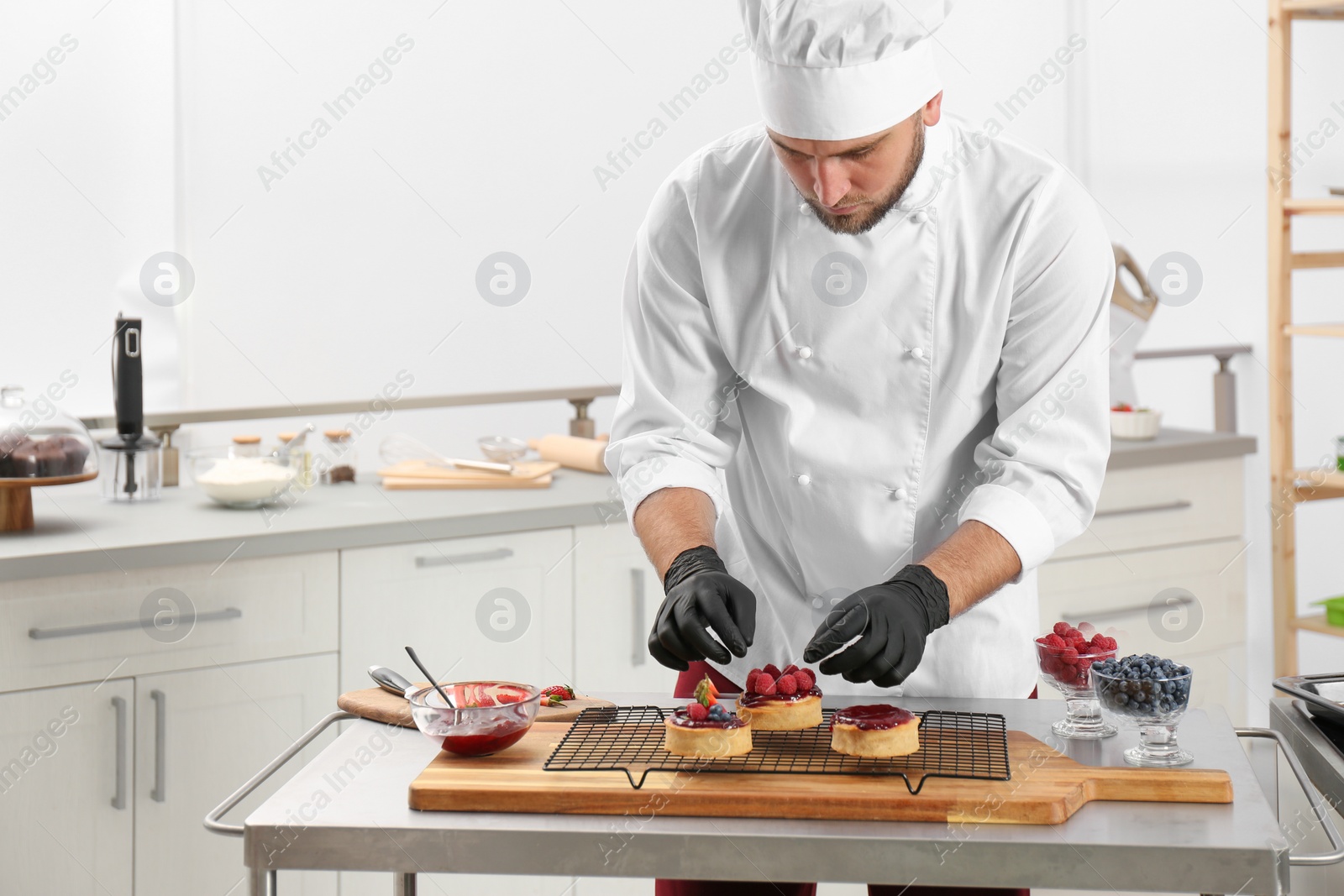 Photo of Male pastry chef preparing desserts at table in kitchen