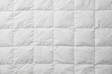 Photo of Soft quilted blanket as background, top view