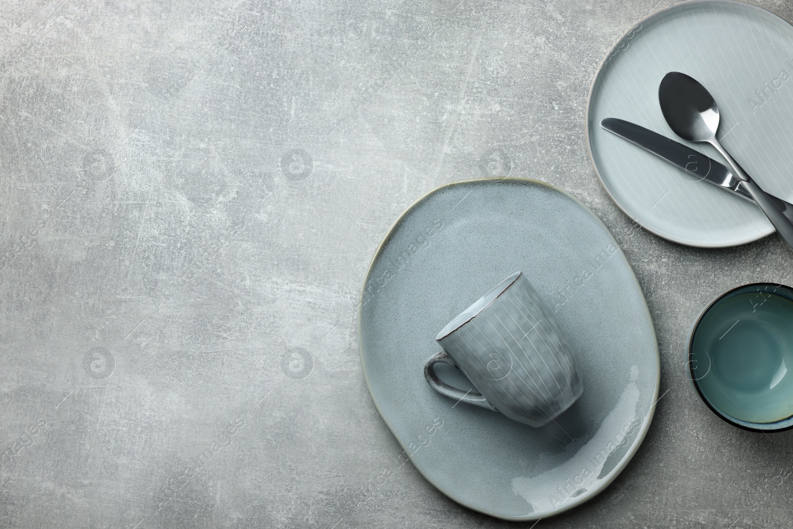 Photo of Stylish empty dishware and cutlery on light grey table, flat lay. Space for text