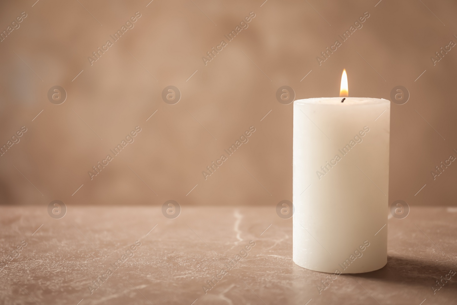 Photo of Beautiful burning wax candle on table against grey background