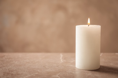 Photo of Beautiful burning wax candle on table against grey background