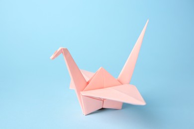 Origami art. Handmade paper crane on light blue background