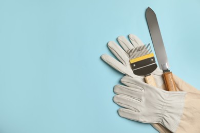 Photo of Beekeeping tools and gloves on light blue background, flat lay. Space for text