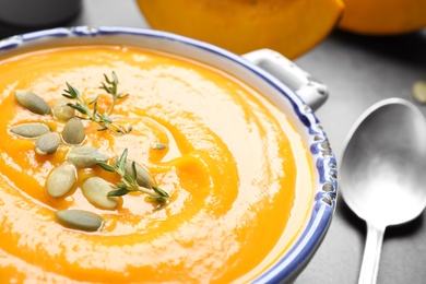 Delicious pumpkin soup in bowl on grey table, closeup