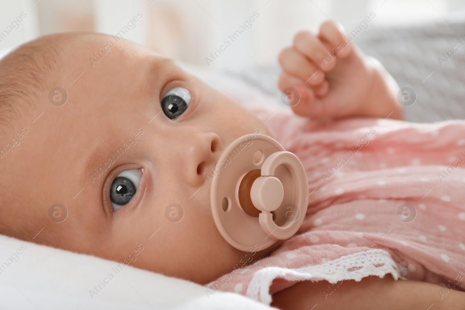 Photo of Cute little baby with pacifier lying in crib, closeup