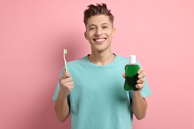 Photo of Young man with mouthwash and toothbrush on pink background