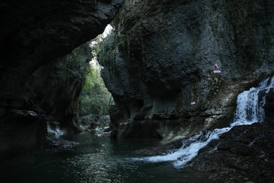 Picturesque view of clean river near cliffs and waterfall outdoors