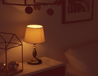 Photo of Lamp and stylish candle holders on table in room