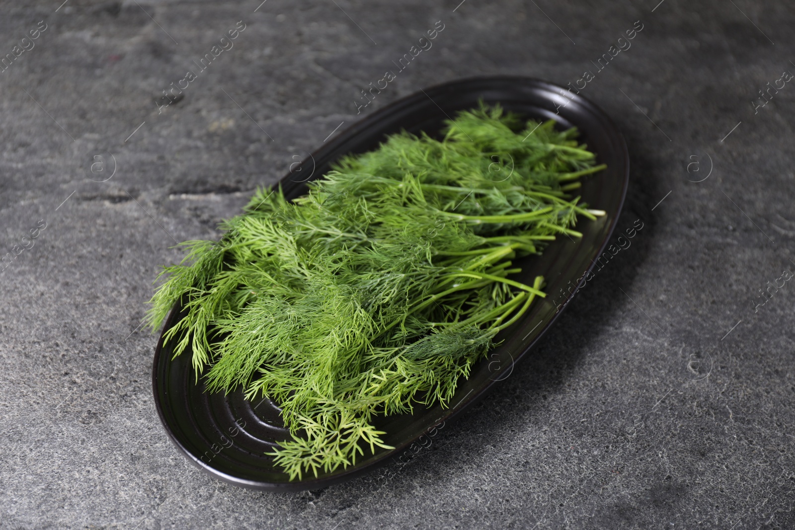 Photo of Sprigs of fresh green dill on grey table