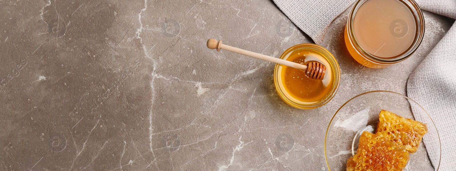 Image of Tasty honey and combs on brown marble table, flat lay with space for text. Banner design