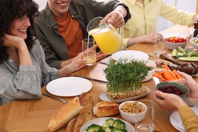 Photo of Friends eating vegetarian food at wooden table indoors