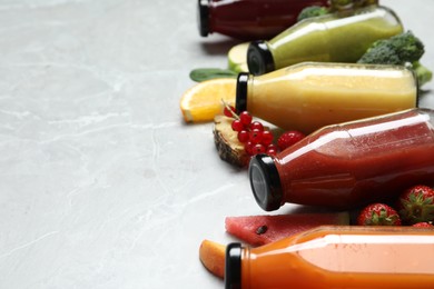 Photo of Bottles of delicious juices and fresh fruits on marble table, closeup. Space for text