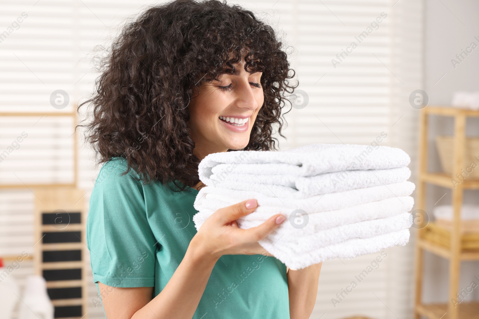 Photo of Beautiful woman with clean laundry at home