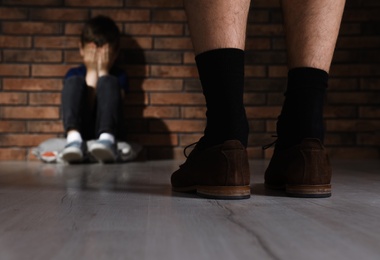 Adult man without pants standing in front of scared little boy indoors. Child in danger