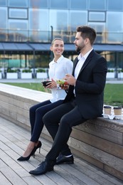 Photo of Business people eating from lunch boxes outdoors