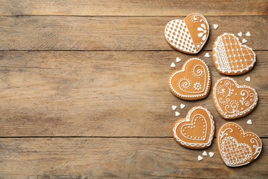 Photo of Tasty heart shaped gingerbread cookies on wooden table table, flat lay. Space for text