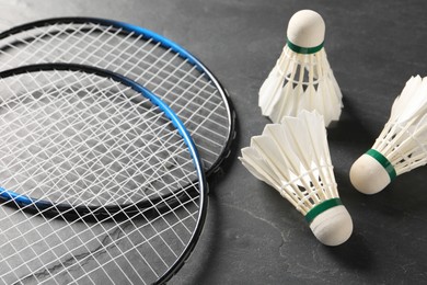 Photo of Feather badminton shuttlecocks and rackets on grey textured table, closeup