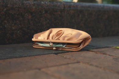 Photo of Beige leather purse on pavement outdoors, closeup. Lost and found