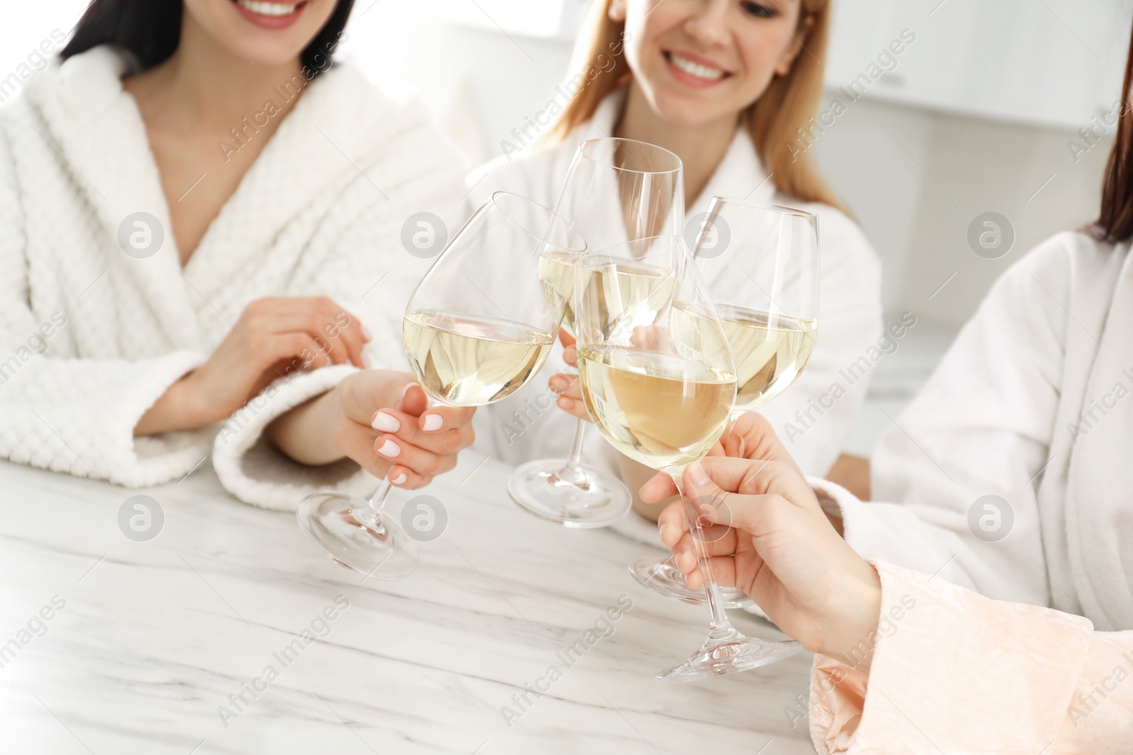 Photo of Beautiful young ladies clinking glasses of wine in kitchen, closeup. Women's Day