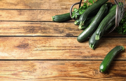 Photo of Basket with green zucchinis on wooden table. Space for text