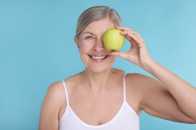 Photo of Beautiful woman with fresh apple on light blue background. Vitamin rich food