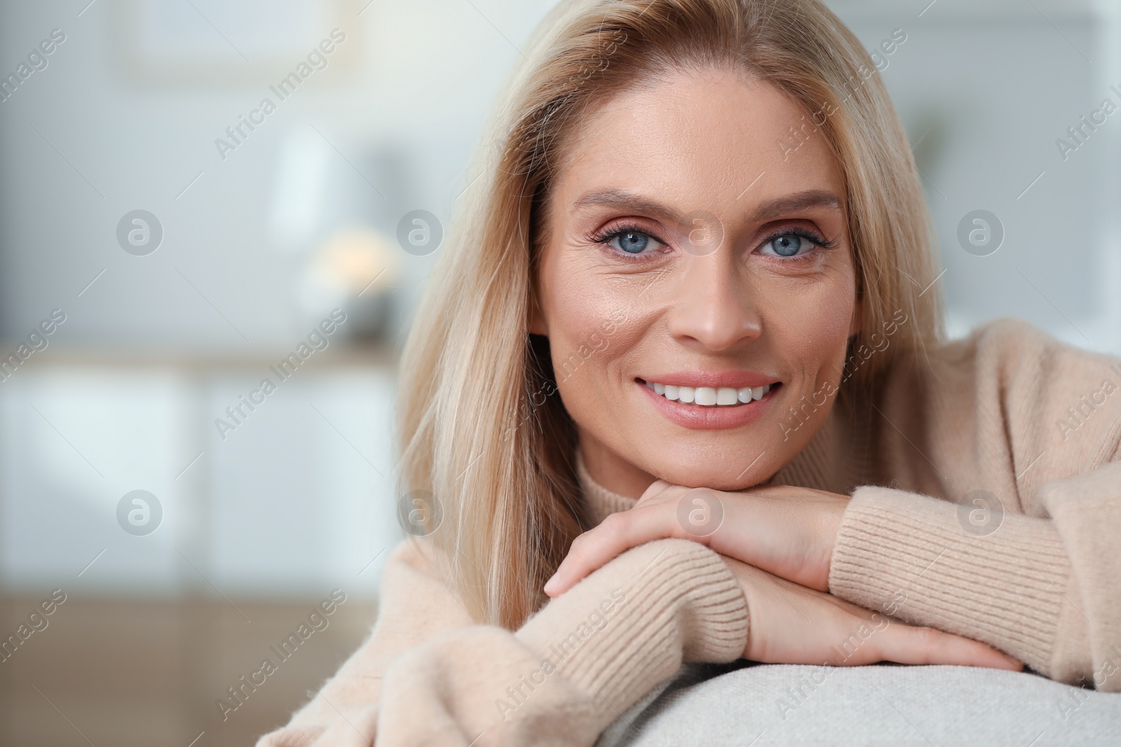 Photo of Portrait of smiling middle aged woman with blonde hair indoors. Space for text