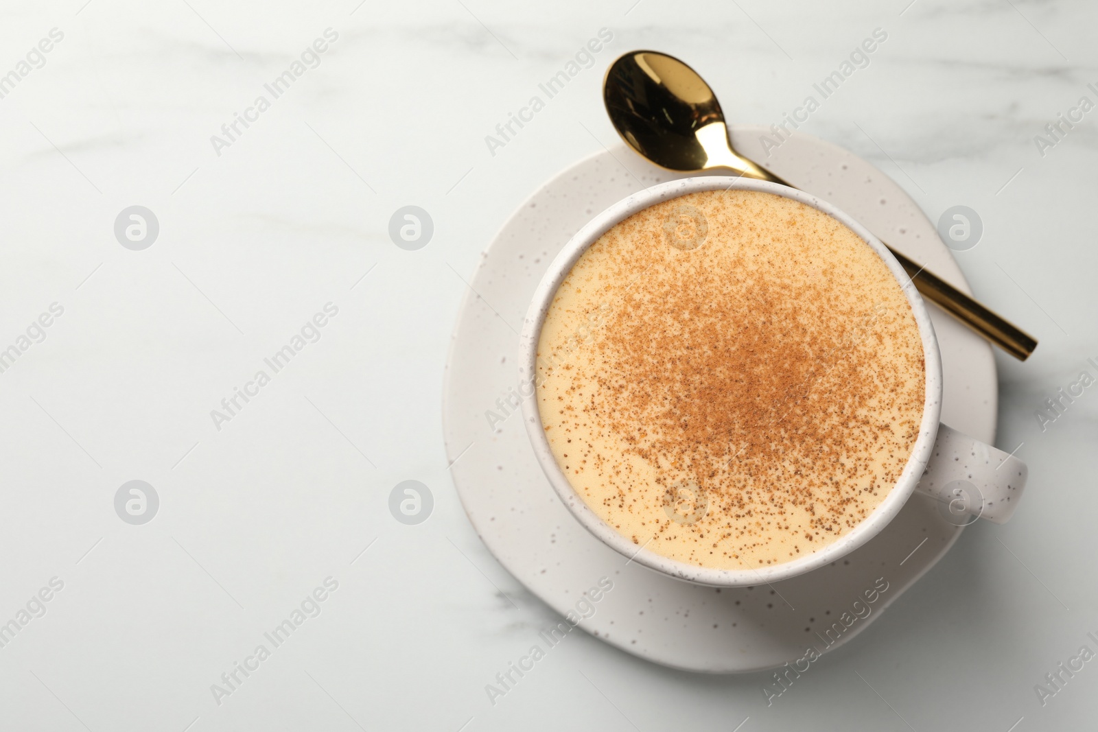 Photo of Delicious eggnog with cinnamon on white marble table, top view. Space for text