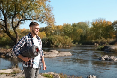 Male camper with sleeping bag near pond. Space for text