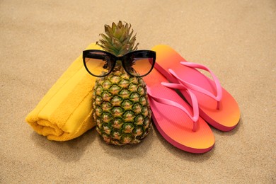 Photo of Fresh pineapple, sunglasses. towel and flip flops on sand