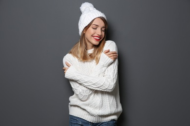 Beautiful young woman in warm sweater with hat on dark background