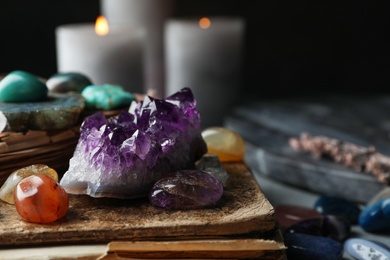 Photo of Many different gemstones and blurred candles on background