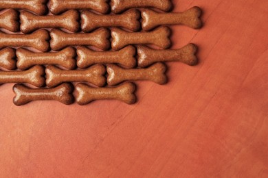 Photo of Bone shaped dog cookies on wooden background, flat lay. Space for text