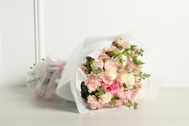 Beautiful bouquet of fresh flowers on wooden table near white wall