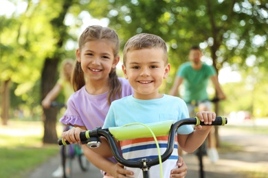 Photo of Happy siblings and their parents riding bicycles in park