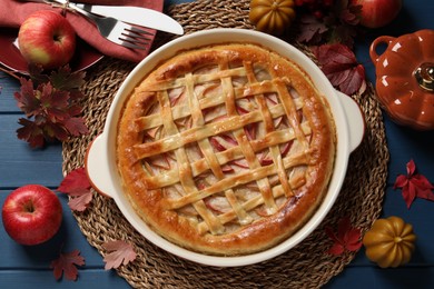 Photo of Delicious homemade apple pie and autumn decor on blue wooden table, flat lay. Thanksgiving Day celebration