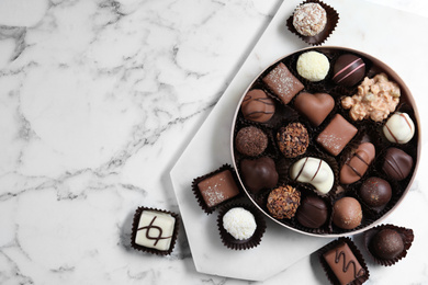 Photo of Different tasty chocolate candies on white marble table, flat lay. Space for text