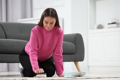 Photo of Woman with brush removing pet hair from carpet at home, space for text